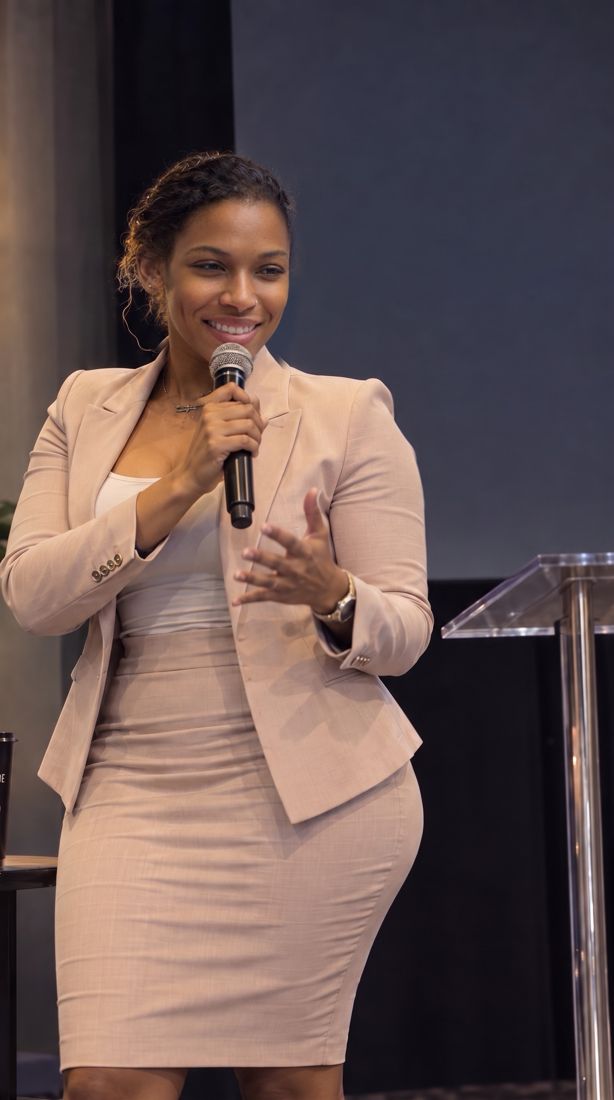 Dr. Gee speaking in a blush suit on stage