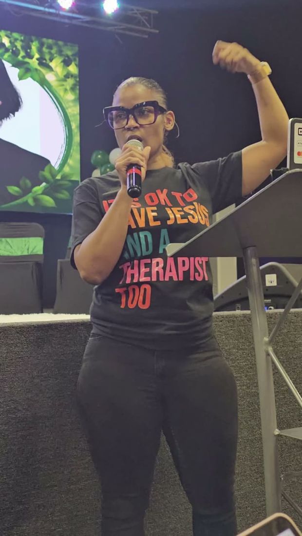 Dr. Gee on stage, microphone in hand, raising one arm to the audience