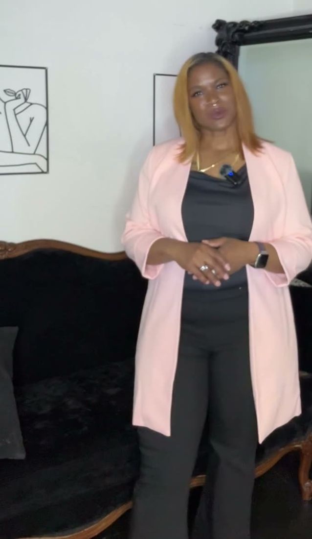 Dr. Gee in a pink blazer standing in a softly lit studio